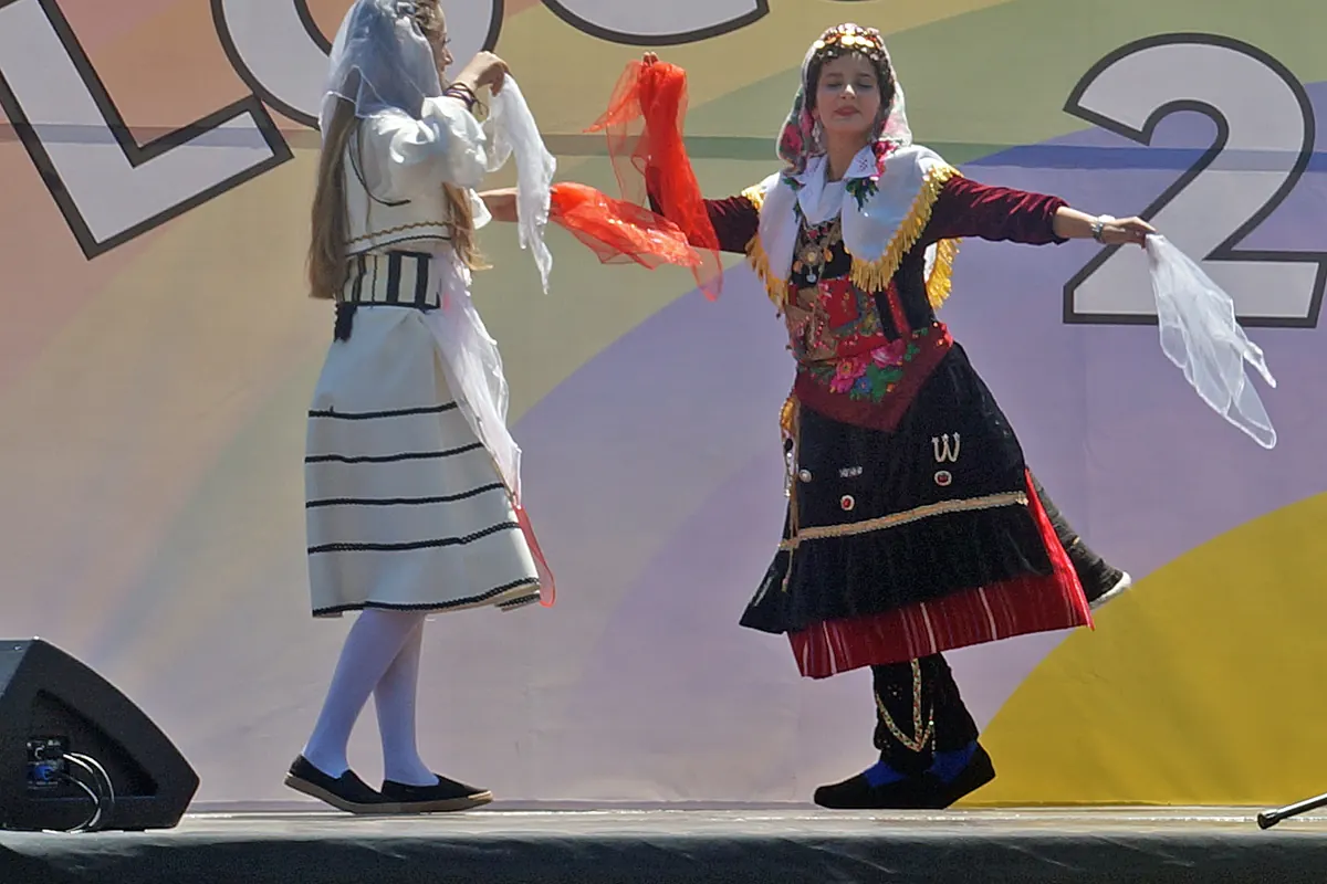 Dos bailarines con traje regional y largos pañuelos se giran el uno hacia el otro sobre un escenario